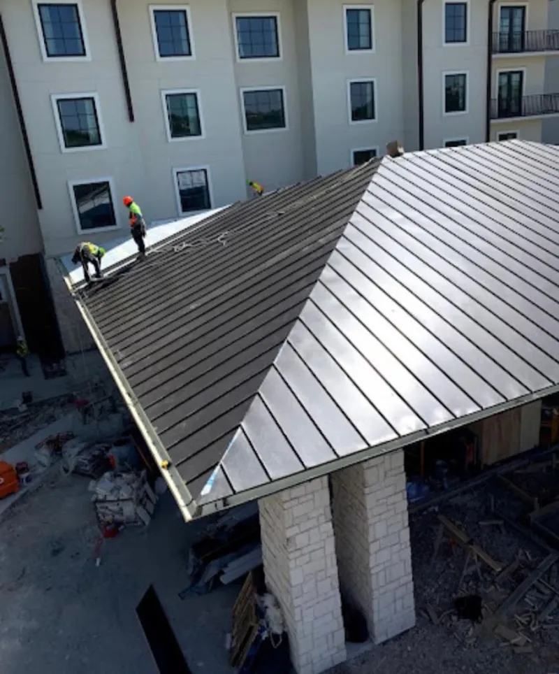 Crew installing standing seam metal roof panels on a commercial project in Athens